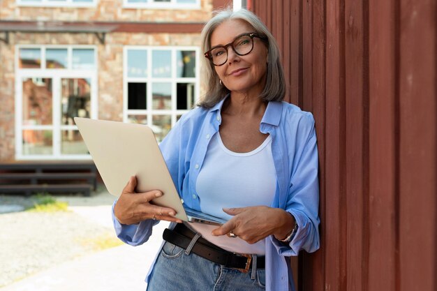 Foto mujer de mediana edad muy a la moda con cabello gris vestida de verano trabajo freelance y caminando hacia abajo