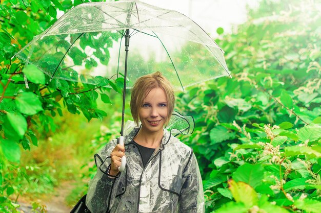 Una mujer de mediana edad bajo un paraguas transparente en otoño en el follaje.
