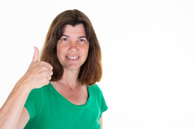 Mujer de mediana edad de pie sobre fondo blanco aislado apuntando con el pulgar hacia arriba a un lado copia espacio sonriendo feliz