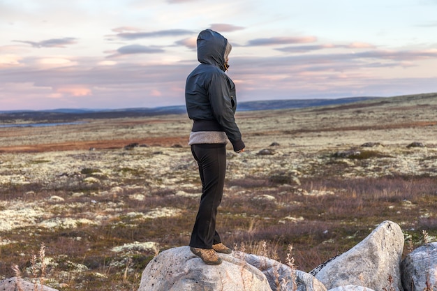 Una mujer de mediana edad de pie sobre la piedra grande en la tundra, concepto de viaje