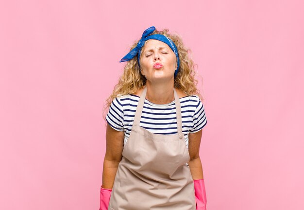 Foto mujer de mediana edad presionando los labios junto con una expresión linda, divertida, feliz y encantadora, enviando un beso concepto de ama de llaves