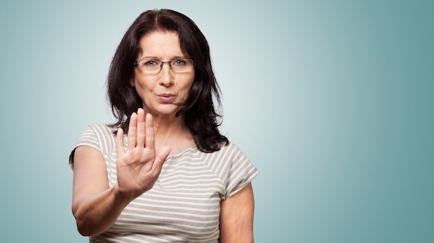 Mujer de mediana edad que muestra la señal de stop