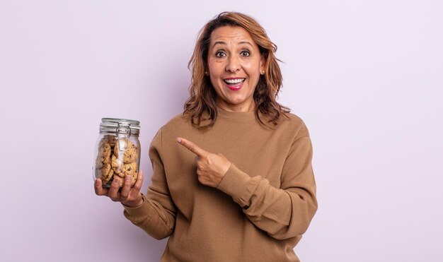 Mujer de mediana edad que parece emocionada y sorprendida señalando el concepto de galletas caseras laterales