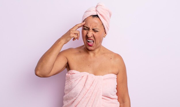 Mujer de mediana edad que parece infeliz y estresada, gesto de suicidio haciendo signo de pistola. concepto de belleza y ducha