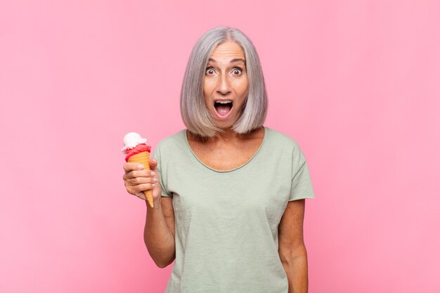 Mujer de mediana edad que parece muy conmocionada o sorprendida, mirando con la boca abierta aislada