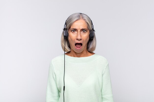 Mujer de mediana edad que parece muy conmocionada o sorprendida, mirando con la boca abierta diciendo wow. concepto de musica