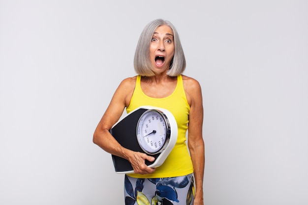 Mujer de mediana edad que parece muy conmocionada o sorprendida, mirando con la boca abierta diciendo wow