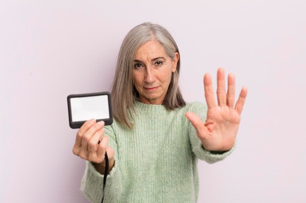 Mujer de mediana edad que parece seria mostrando la palma abierta haciendo un gesto de parada concepto de pase vip