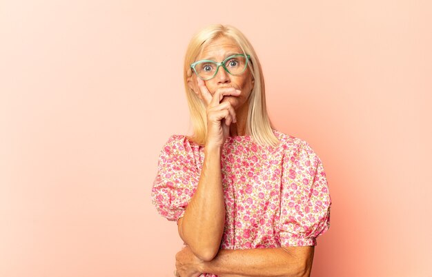 Mujer de mediana edad que parece seria, pensativa y desconfiada, con un brazo cruzado y la mano en la barbilla, opciones de ponderación