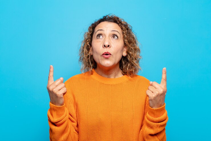 Foto mujer de mediana edad que se siente asombrada y con la boca abierta apuntando hacia arriba con una mirada conmocionada y sorprendida