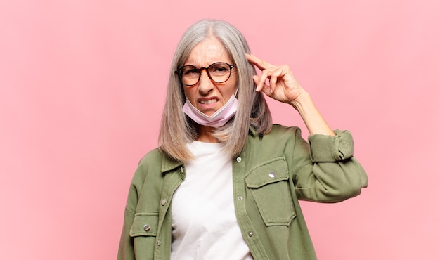 Mujer de mediana edad que se siente confundida y perpleja, mostrando que está loco, loco o loco