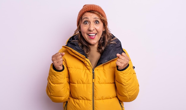 Mujer de mediana edad que se siente conmocionada, riendo y celebrando el éxito. concepto de invierno