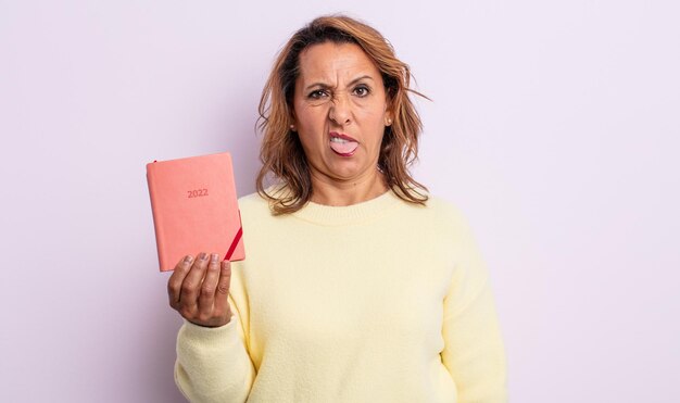 Mujer de mediana edad que se siente disgustada e irritada y con la lengua fuera. concepto de agenda