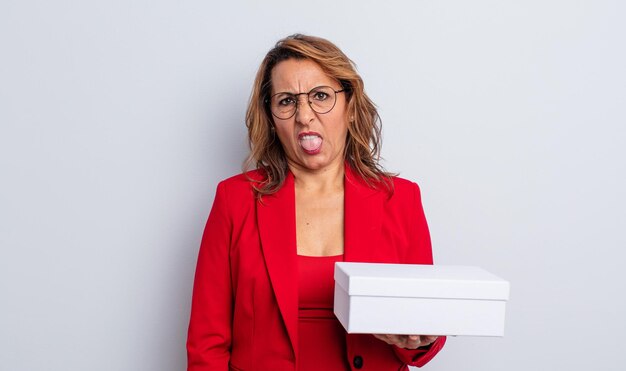 Mujer de mediana edad que se siente disgustada e irritada y con la lengua fuera. paquete de caja blanca