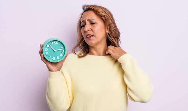 Mujer de mediana edad que se siente estresada, ansiosa, cansada y frustrada. concepto de reloj despertador