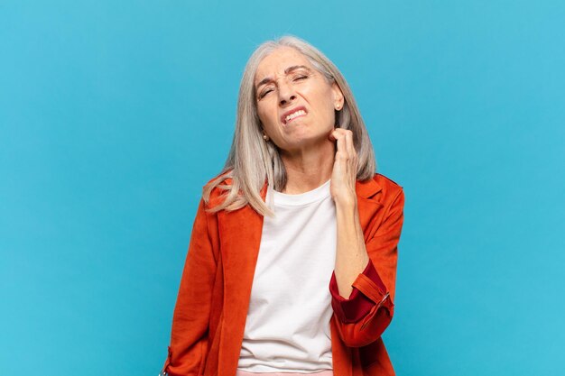 mujer de mediana edad que se siente estresada, frustrada y cansada, frotando el cuello doloroso, con una mirada preocupada y preocupada