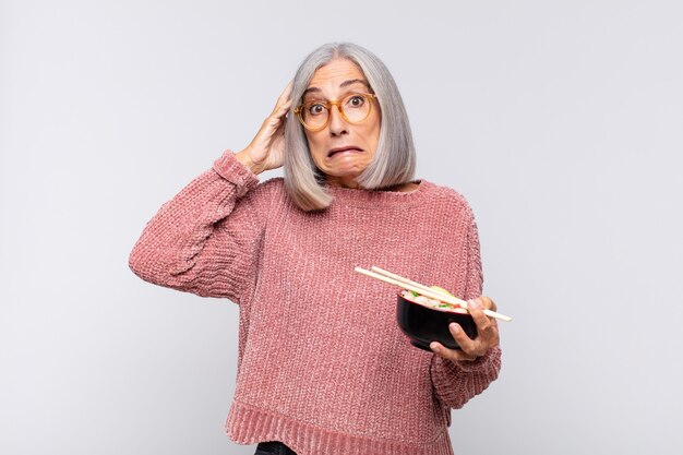 Mujer de mediana edad que se siente estresada, preocupada, ansiosa o asustada, con las manos en la cabeza, en pánico por el concepto de comida asiática de error