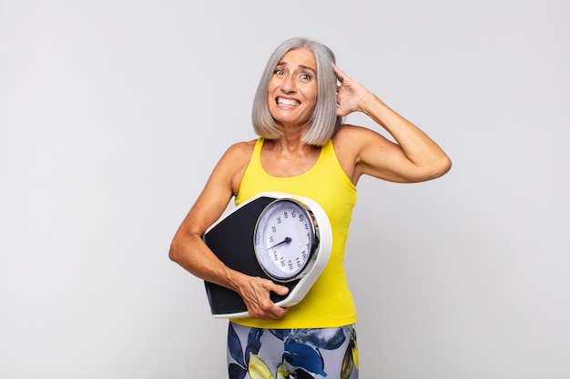 Mujer de mediana edad que se siente estresada, preocupada, ansiosa o asustada, con las manos en la cabeza, presa del pánico por el error. concepto de fitness