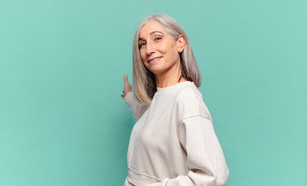 Foto mujer de mediana edad que se siente feliz y alegre, sonriendo y dándote la bienvenida, invitándote con un gesto amistoso