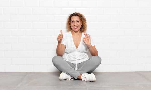 Mujer de mediana edad que se siente feliz, asombrada, satisfecha y sorprendida, mostrando gestos de aprobación y pulgar hacia arriba