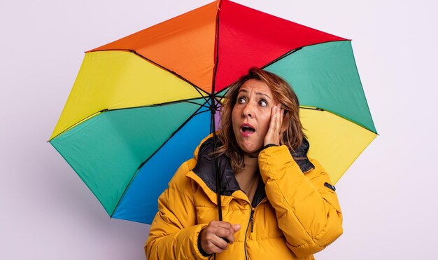 Mujer de mediana edad que se siente feliz, emocionada y sorprendida. concepto de paraguas