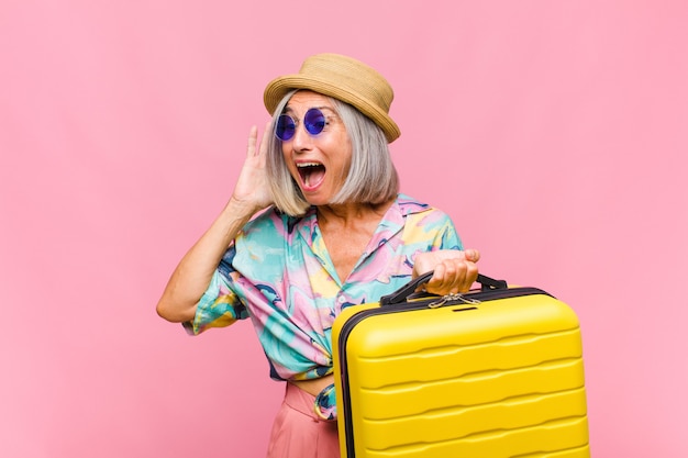 Mujer de mediana edad que se siente feliz, emocionada y sorprendida, mirando hacia el lado con ambas manos en la cara