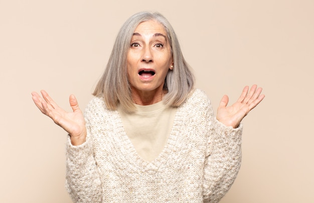 Mujer de mediana edad que se siente feliz, emocionada, sorprendida o conmocionada, sonriendo y asombrada por algo increíble