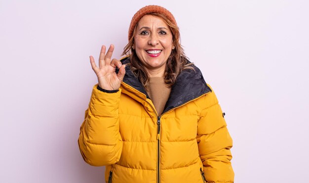 Mujer de mediana edad que se siente feliz, mostrando aprobación con gesto bien. concepto de invierno