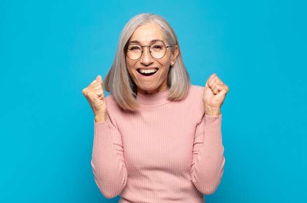 Mujer de mediana edad que se siente feliz, positiva y exitosa, celebrando la victoria, los logros o la buena suerte