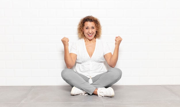 Mujer de mediana edad que se siente feliz, positiva y exitosa, celebrando la victoria, los logros o la buena suerte