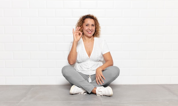 Mujer de mediana edad que se siente feliz, relajada y satisfecha, mostrando aprobación con gesto bien, sonriendo