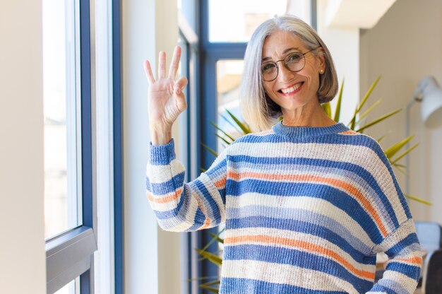 Foto mujer de mediana edad que se siente feliz, relajada y satisfecha, mostrando aprobación con gesto bien, sonriendo