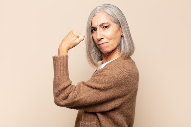 Mujer de mediana edad que se siente feliz, satisfecha y poderosa, con ajuste de flexión y bíceps musculosos, luciendo fuerte después del gimnasio