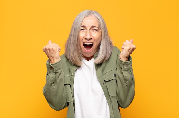 Mujer de mediana edad que se siente feliz, sorprendida y orgullosa, gritando y celebrando el éxito con una gran sonrisa