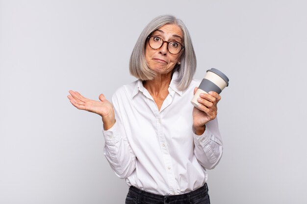 Mujer de mediana edad que se siente perpleja y confundida, dudando, ponderando o eligiendo diferentes opciones con el concepto de café de expresión divertida