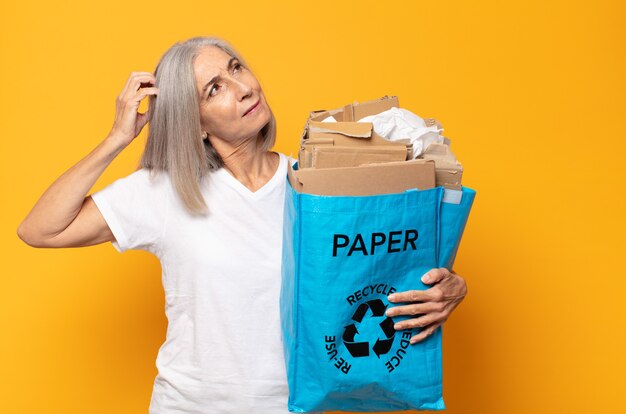 Mujer de mediana edad que se siente perpleja y confundida, rascándose la cabeza y mirando hacia un lado