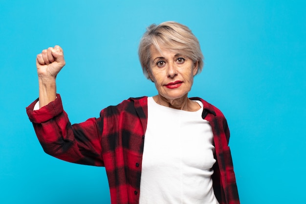 Mujer de mediana edad que se siente seria, fuerte y rebelde, levanta el puño, protesta o lucha por la revolución