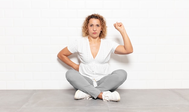 Mujer de mediana edad que se siente seria, fuerte y rebelde, levanta el puño, protesta o lucha por la revolución