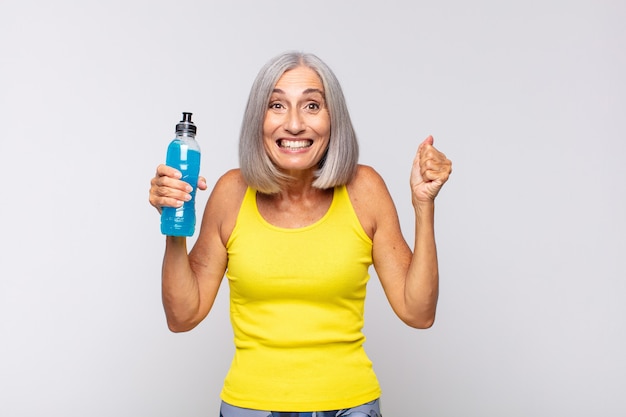 Mujer de mediana edad que se siente sorprendida, emocionada y feliz, riendo y celebrando el éxito, diciendo ¡guau !. concepto de fitness