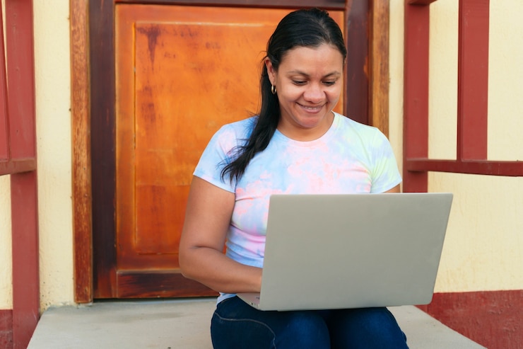Foto mujer de mediana edad que trabaja con su computadora portátil fuera de su casa