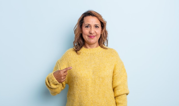 Mujer de mediana edad que se ve orgullosa, segura y feliz, sonriendo y apuntando a sí misma o haciendo la señal número uno