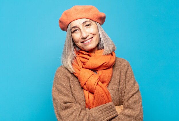 Mujer de mediana edad riendo alegremente con los brazos cruzados, con una pose relajada, positiva y satisfecha