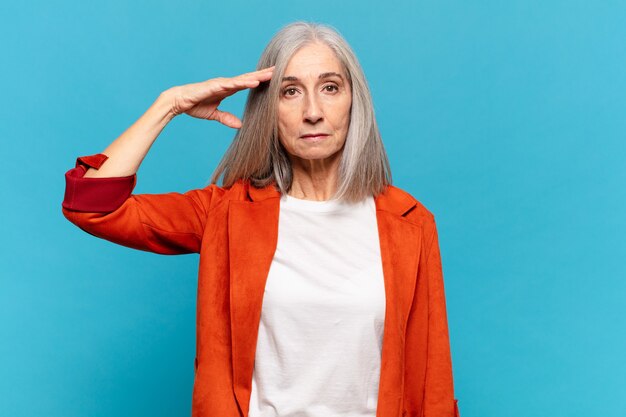 Mujer de mediana edad con un saludo militar en un acto de honor y patriotismo, mostrando respeto