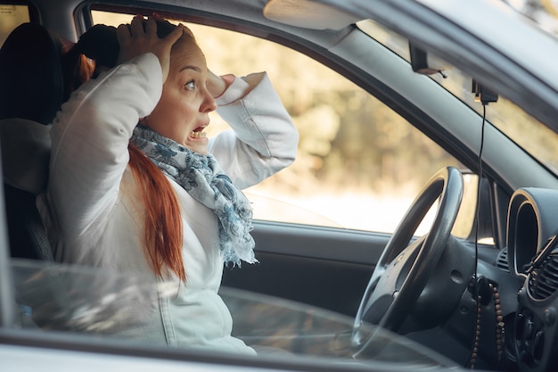 Mujer de mediana edad se sienta en el automóvil y se queja de la situación del tráfico