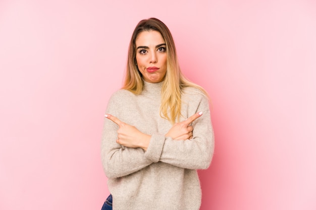 Mujer de mediana edad sobre puntos de pared de lado, está tratando de elegir entre dos opciones.