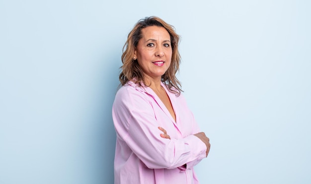 Foto mujer de mediana edad sonriendo a la cámara con los brazos cruzados y una expresión feliz, segura y satisfecha, vista lateral