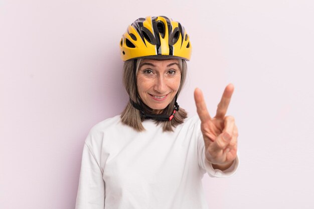 Mujer de mediana edad sonriendo y luciendo amigable mostrando el concepto de casco de bicicleta número dos