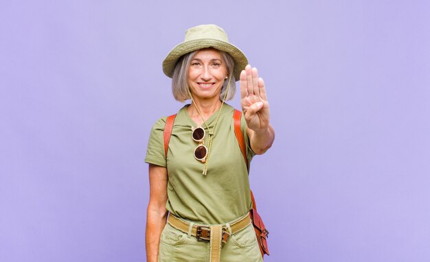 Mujer de mediana edad sonriendo y mirando amigable, mostrando el número cuatro o cuarto con la mano hacia adelante, contando hacia atrás