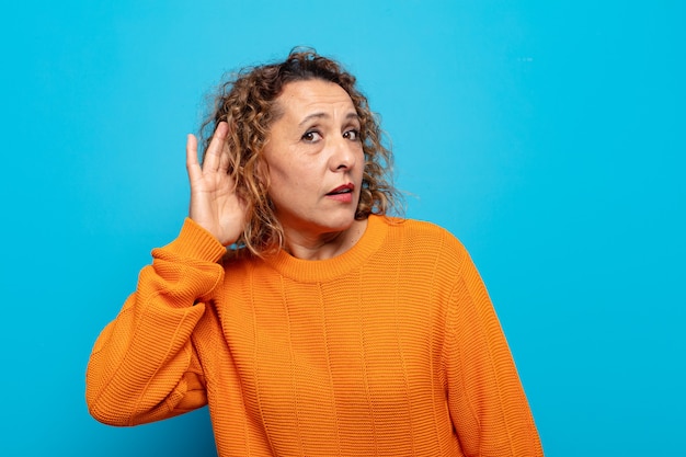 Mujer de mediana edad sonriendo, mirando con curiosidad hacia un lado, tratando de escuchar chismes o escuchar un secreto