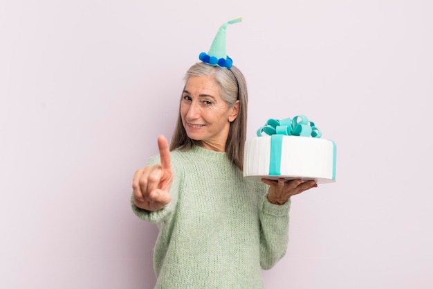 Mujer de mediana edad sonriendo con orgullo y confianza haciendo el concepto de pastel de cumpleaños número uno